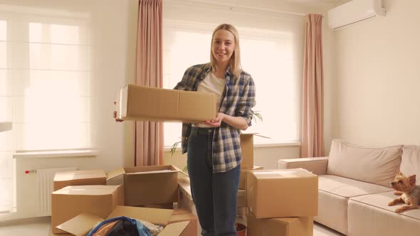 A Happy Woman Holds a Cardboard Moving Box in Her Hands