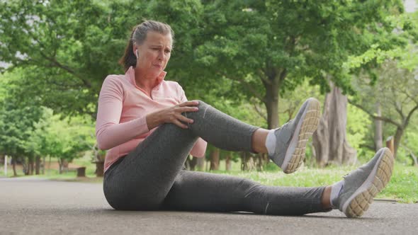 Senior woman in pain holding her leg in the park