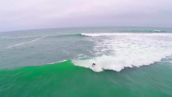 Aerial view of a surfer riding a wave while surfing