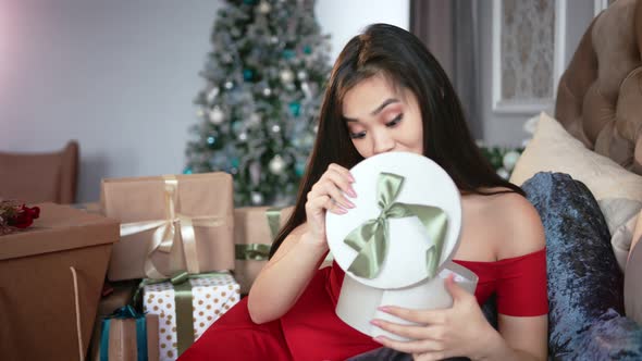 Anticipant Elegant Young Asian Woman Opening Christmas Gift Box and Smiling