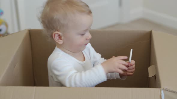 Baby Playing in Large Cardboard Package Box at Home