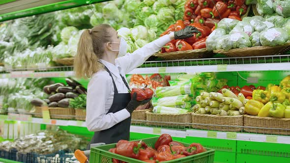 Female Puts Red Pepper on a Shelf in an Organic Store Young Woman in Medical Mask Replenishes