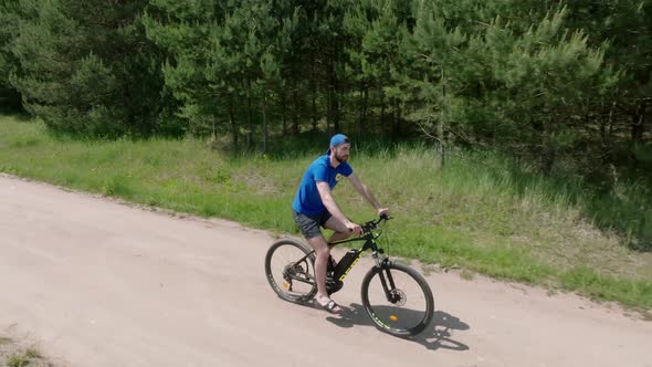 Close Up of a Biker Riding a Bike Through the Forest Road