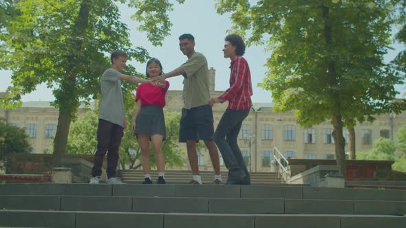 Cheerful Diverse Multiracial College Students Making Pile of Hands at Campus