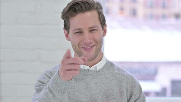 Portrait of Cheerful Young Man Pointing at the Camera 