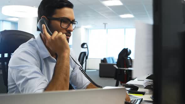 Male executive talking on telephone at desk