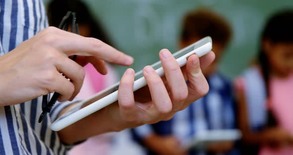 Teacher standing holding digital tablet