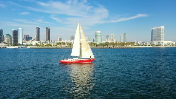 Red sailboat on the San Diego Bay with a view of San Diego's skyline