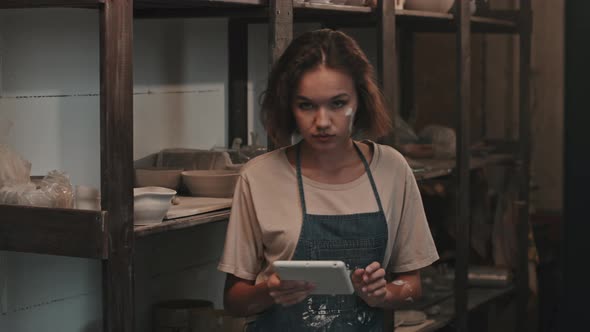 Female Ceramist Posing by Rack