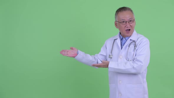 Happy Mature Japanese Man Doctor Looking Excited While Showing Something