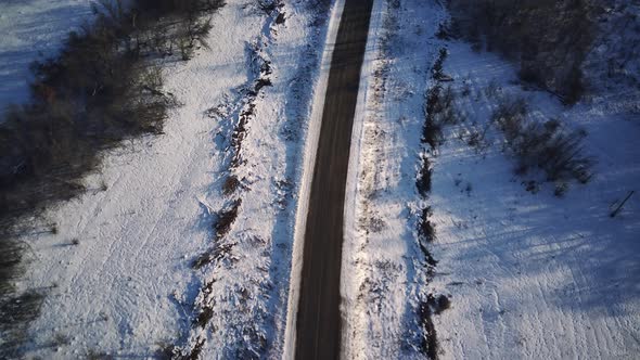 Aerial view of an asphalt road surrounded by snow