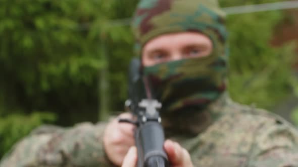 Closeup of a Masked Soldier Preparing to Fire and Pointing the Machine Gun Towards the Camera