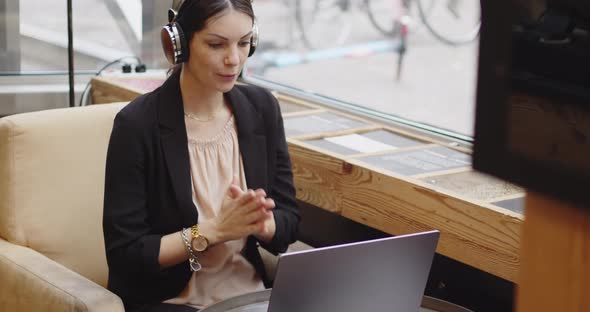 Young Caucasian Woman with Headphones During a Meeting Conference in a Public Bar