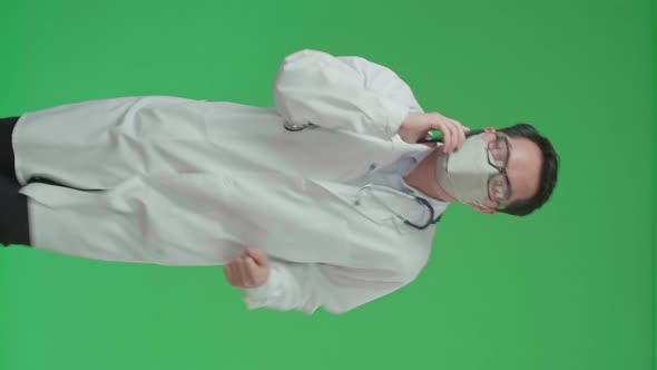 Asian Doctor With Stethoscope Wearing Mask, Talking On Mobile Phone While Running On Green Screen