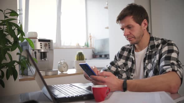 Man Works at Home Office with Laptop and Documents
