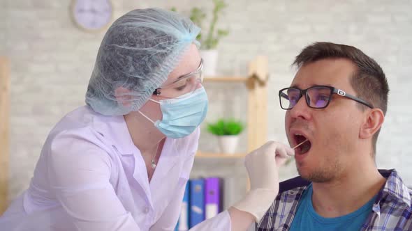 Woman Lab Technician Taking a Saliva Test From a Man's Mouth with a Cotton Swab Slow Mo