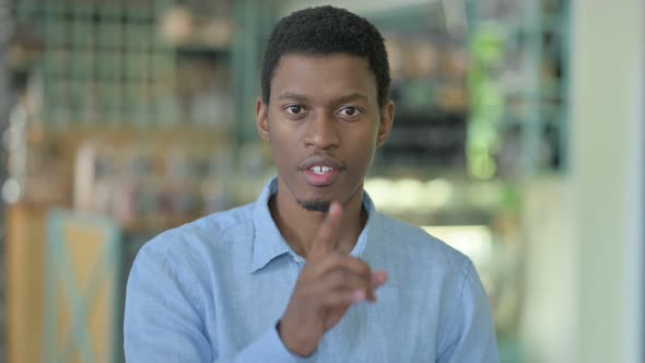 Young African Man Putting Finger on Lips 