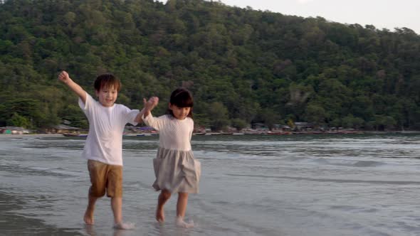 Happy asian family with boy and girl playful running on the beach for relax in vacation together.