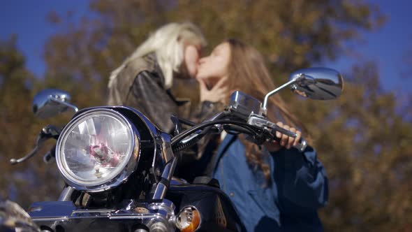 Two Millenial Girls Sensualy Kissing on the Mounted Bike  Low Angle View
