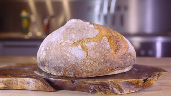 Loaf Of Sourdough Bread In The Kitchen. Man With Tattoo Walks In The Background - pan shot, selectiv