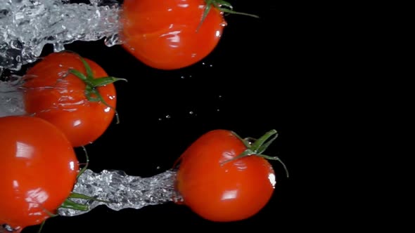 Group of Wet Red Cherry Tomatoes are Flying Horizontally on the Black Background