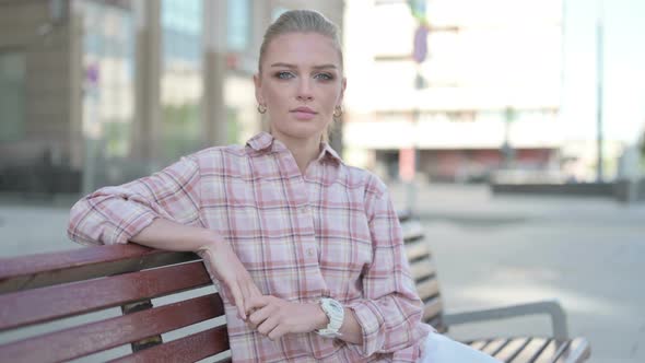 Young Woman Looking at Camera While Sitting on Bench