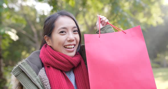 Happy woman holding paper bag at park