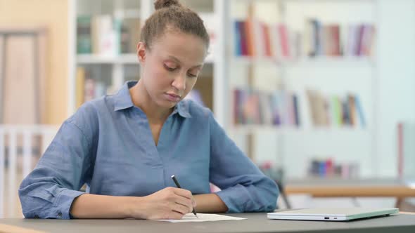 Young African Woman Thinking and Doing Paperwork