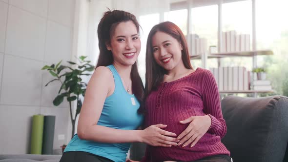 Pregnant Asian lesbian woman and her partner are happy to spend time together at home.