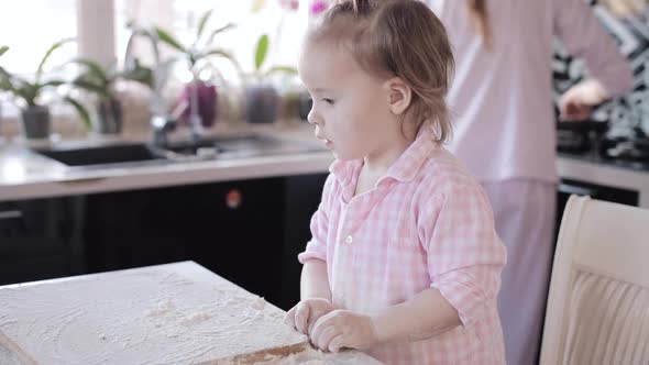 Little Girl Cooking with Caring Mother at Kitchen