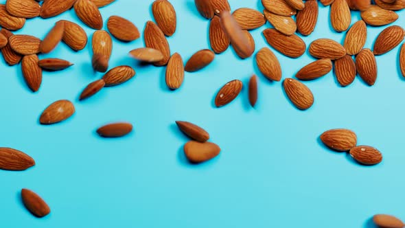 Almonds are falling down on a blue background. The appetizing portion of nuts.