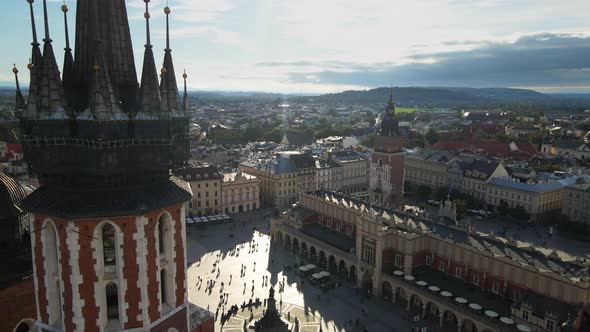 Aerial drone view of Krakow main market square, clock tower, St. Mary's church and people walking ar