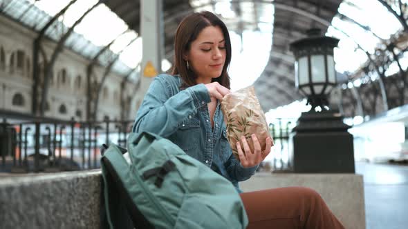 Positive brunette woman tourist eating bun