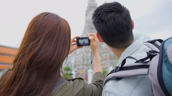 Asian couple backpacker use camera selfie, take picture in the city.