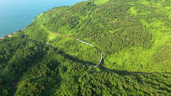 A train passes over a bridge in a scenic mountain pass in Danang Vietnam. Filmed from drone.