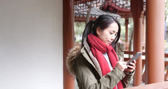 Young asian woman using smart phone in china, beautiful chinese pavilion garden