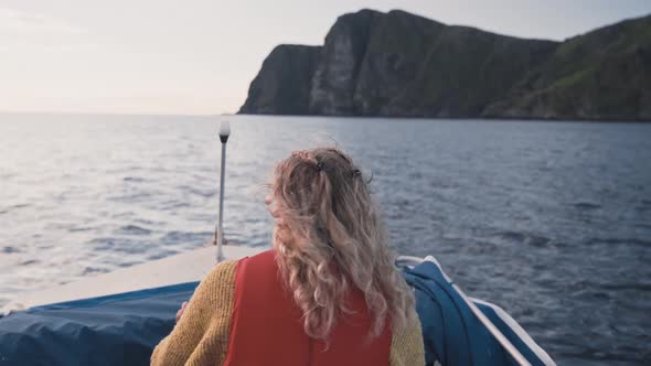 Attractive blonde female boating near Runde island coastline, back view