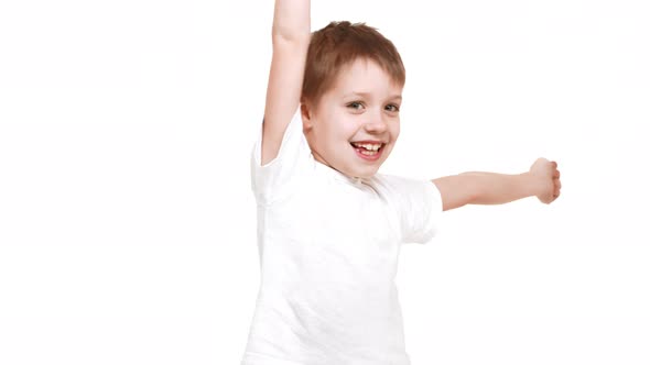 Very Young Cute Caucasian Boy Standing on White Background and Happily Raising Hands Up in Joy