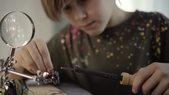 Father Teaching His Little Son to Solder Electronic Contacts at Home