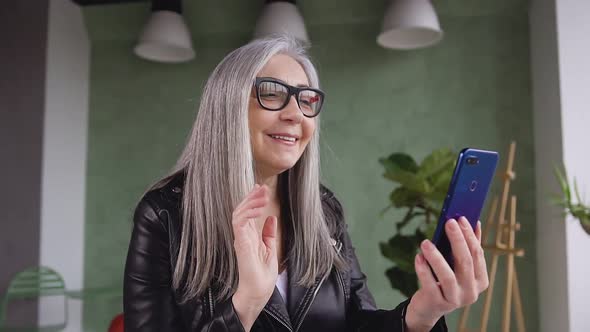 Satisfied 60-Aged Modern Woman in Glasses which Having Video Call with Her Friend on Phone