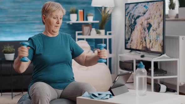 Old Woman Training with Dumbbells to Stretch Arms Muscles