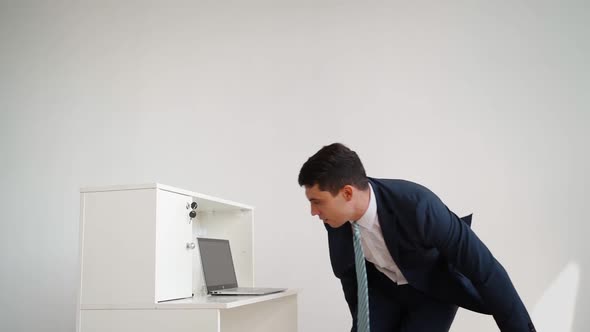 Business Man in Formal Clothes Jumps Over Desk and Sits Down to Work at Laptop