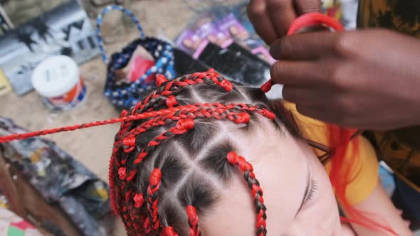 Process of Weaving African Braids with Red Kanekalon Outdoor Zanzibar Africa