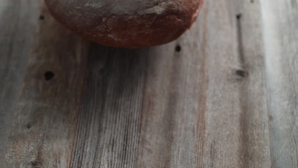 A whole sourdough bread falling on a table. Slow Motion.