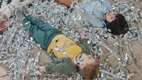 Cute Kids Lying in Bunch of Silver Streamers