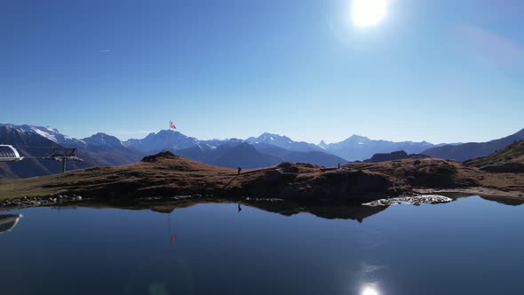 Swiss flag in iconic matterhorn and alpine panorama and silhouette hiker, aerial