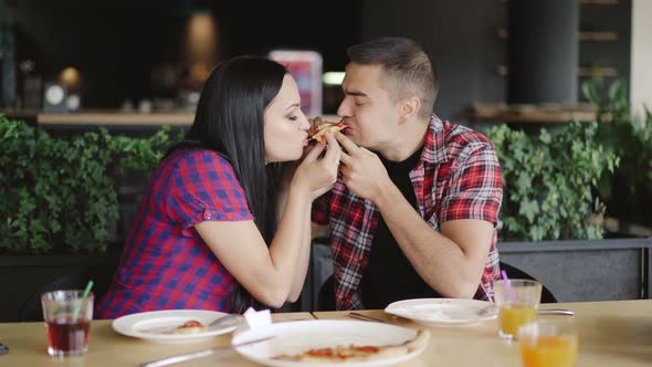 Two People are Eating one Slice of Pizza in the Cafe