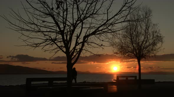 Fussy And Lonely Woman Sitting On The Beach, Empty Bank At Sunset