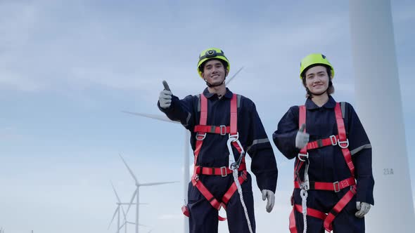 Two maintenance engineers in safety gear working at height are standing with thumb up