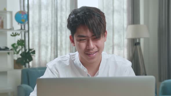 Close Up Of A Happy Asian Man Student Using Computer To Study Online At Home